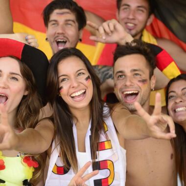 Eine Gruppe von Deutschlandsfans (Frauen und Männer) schauen begeistert einem Fußballspiel zu.
